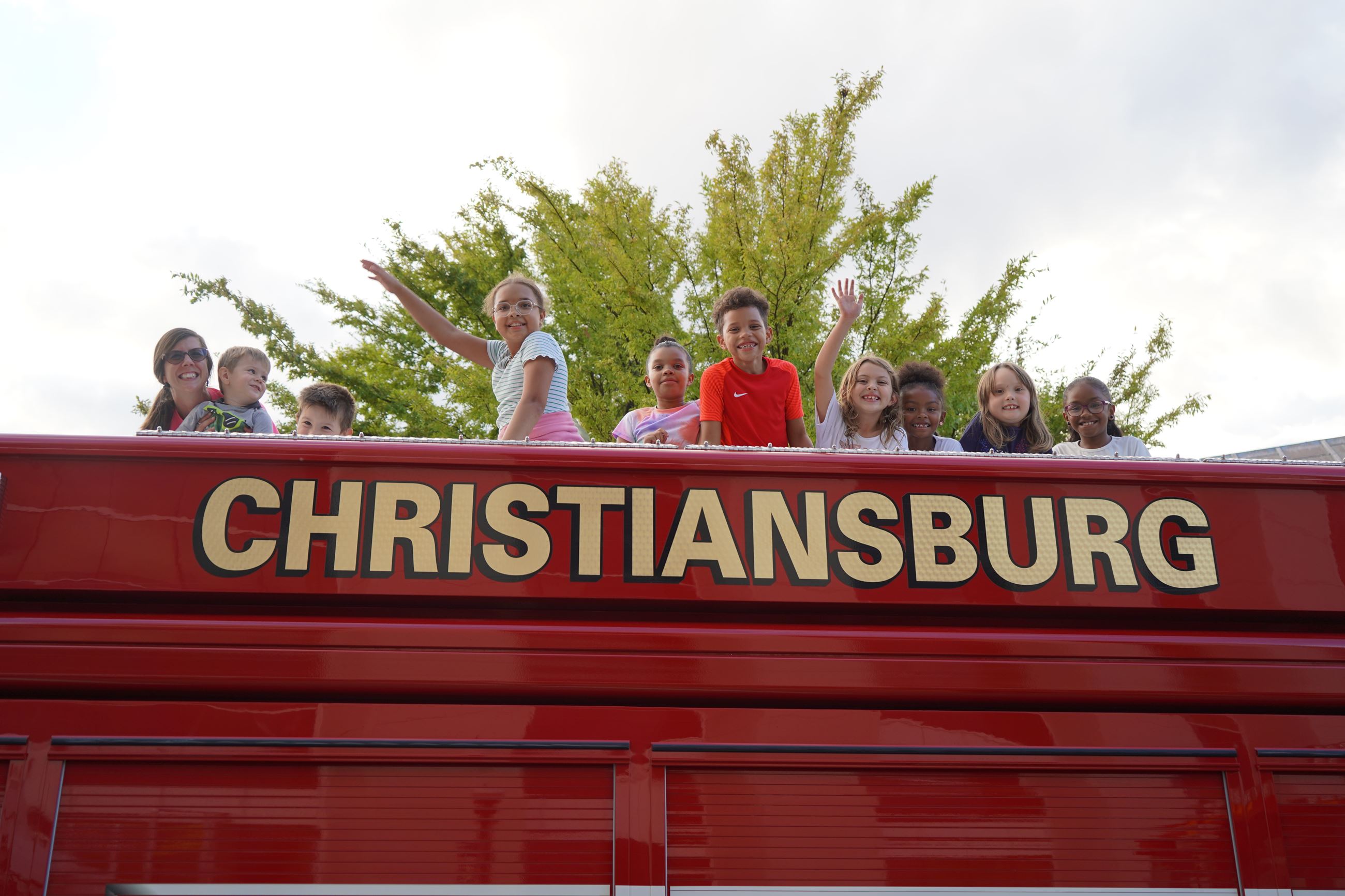 A group of kids sitting on top of a Christiansburg fire truck
